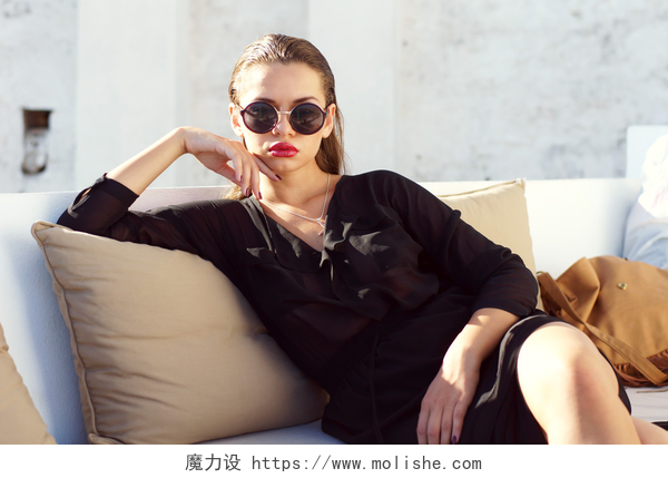 年轻漂亮的女人穿着黑色衣服坐在沙发上户外坐的女人